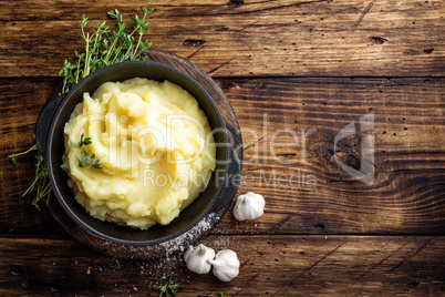 Mashed potatoes, boiled puree in cast iron pot on dark wooden rustic background, top view