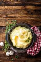 Mashed potatoes, boiled puree in cast iron pot on dark wooden rustic background, top view