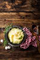 Mashed potatoes, boiled puree in cast iron pot on dark wooden rustic background, top view