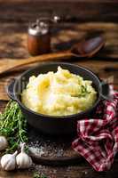 Mashed potatoes, boiled puree in cast iron pot on dark wooden rustic background