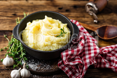 Mashed potatoes, boiled puree in cast iron pot on dark wooden rustic background