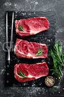 Raw meat, beef steak on black background, top view