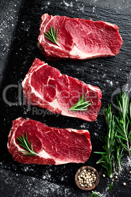 Raw meat, beef steak on black background, top view