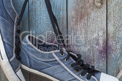 pair of old worn blue shoe hanging on a nail