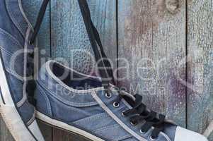 pair of old worn blue shoe hanging on a nail