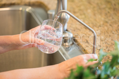 Woman Pouring Fresh Reverse Osmosis Purified Water Into Glass in