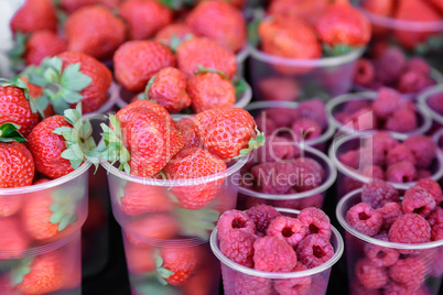 Raspberries and strawberries in containers for sale.