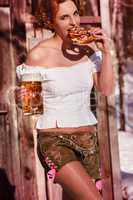 attraktive  Frau in Lederhose mit Bierkrug und Brezel