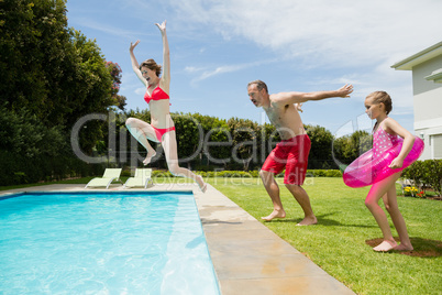 Happy parents and daughter jumping in swimming pool