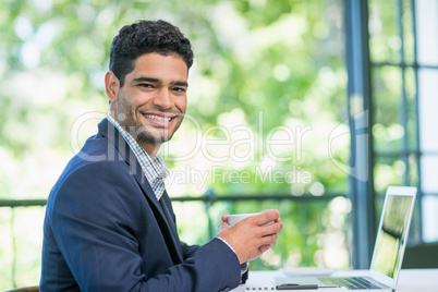 Happy businessman holding coffee cup in a restaurant