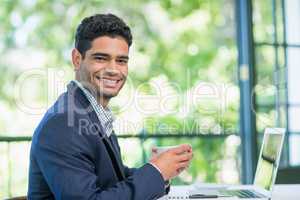 Happy businessman holding coffee cup in a restaurant