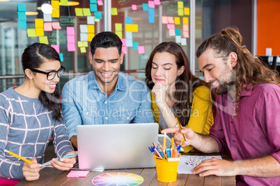 Smiling graphic designers discussing over laptop in meeting