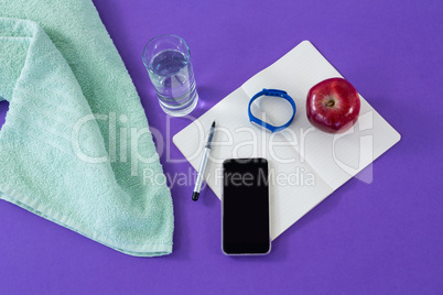 Towel, mobile phone with opened book and apple