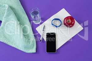 Towel, mobile phone with opened book and apple