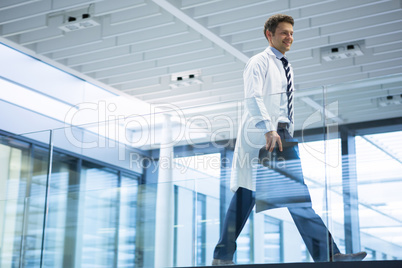 Male doctor walking with x-ray report in corridor