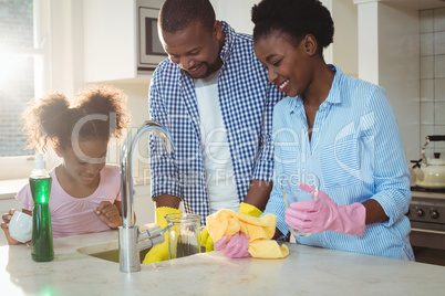 Family washing utensils in kitchen sink