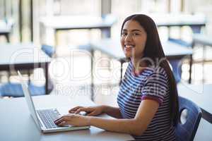Portrait of schoolgirl using laptop in classroom