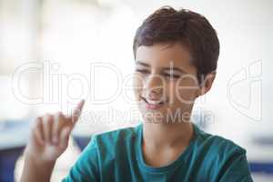 Attentive schoolboy gesturing in classroom