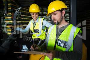 Factory workers maintaining record on clipboard in factory