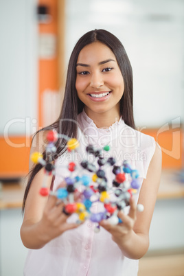 Portrait of happy schoolgirl experimenting molecule model in laboratory