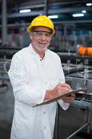 Factory engineer maintaining record on clipboard in factory