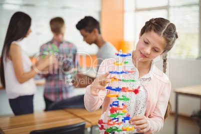 Smiling schoolgirl examining the molecule model in laboratory