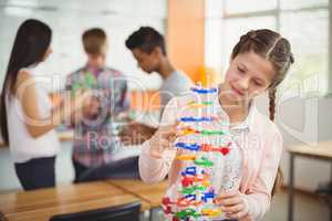 Smiling schoolgirl examining the molecule model in laboratory