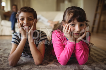 Portrait of siblings lying on rug in living room
