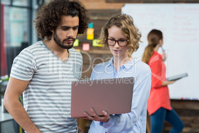 Business executives discussing over laptop