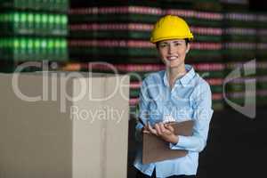 Female factory worker maintaining record on clipboard in factory