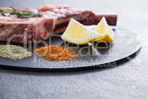 Blade chop, spices and lemon on black round tray