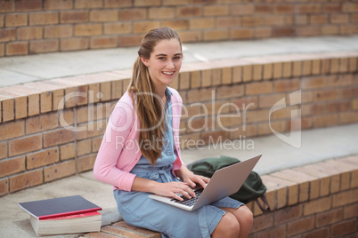 Portrait of schoolgirl using laptop in campus
