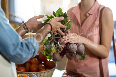 Woman taking beetroot from the vendor at the grocery store