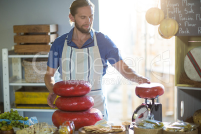 Salesman weighing gouda cheese at counter