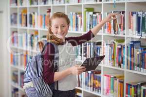 Portrait of happy schoolgirl selecting book in library
