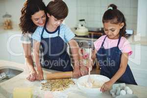 Mother and kids preparing cookies in kitchen