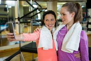 Beautiful fit women taking selfie on mobile phone after workout