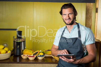 Smiling shop assistant using digital tablet