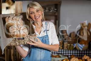 Female staff holding basket of sweet foods in bakery section