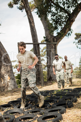 Young military soldiers practicing tyre obstacle course