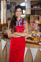 Portrait of smiling female staff standing with arms crossed at bakery shop