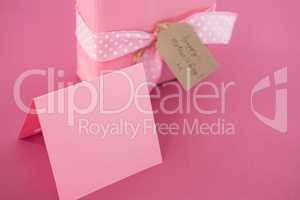 Gift box with blank card and flower cup against pink background