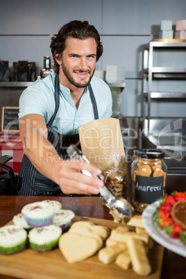 Portrait of staff packing a bread in paper bag at counter