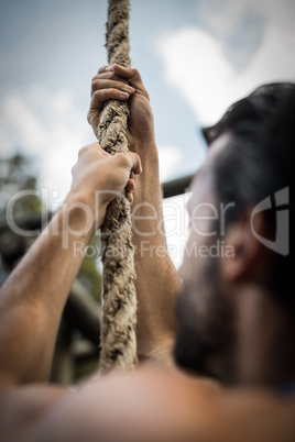 Man climbing a rope during obstacle course Man climbing a rope during obstacle course