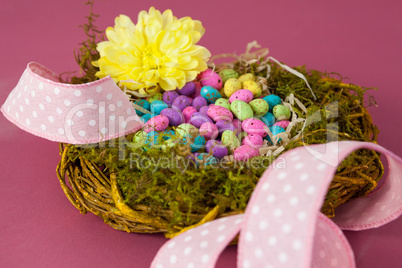 Colorful easter eggs in wicker basket with a flower