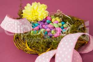 Colorful easter eggs in wicker basket with a flower