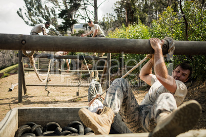 Young military soldiers practicing rope climbing during obstacle course