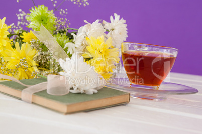 Cup of tea with flowers and book on table