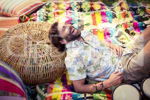 Man holding beer bottle and relaxing on wicker stool at campsite