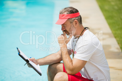 Swim coach looking at clipboard near poolside